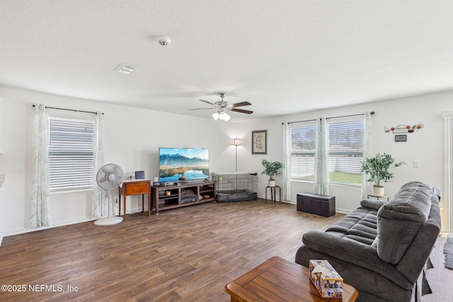 living room with ceiling fan, wood finished floors, visible vents, and baseboards