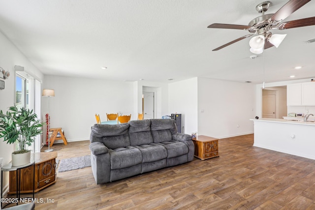 living room with baseboards, a ceiling fan, wood finished floors, and recessed lighting