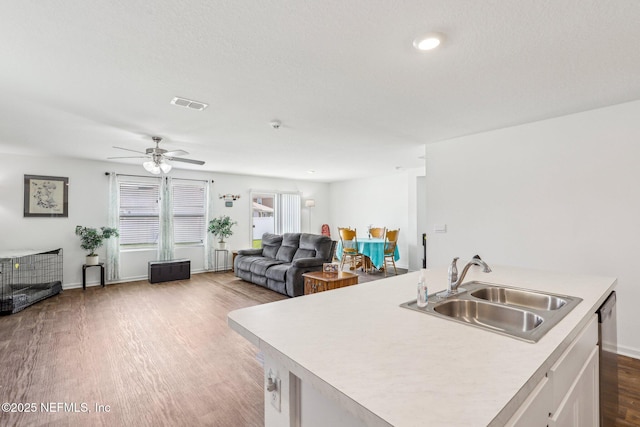 kitchen featuring light countertops, visible vents, open floor plan, a sink, and wood finished floors