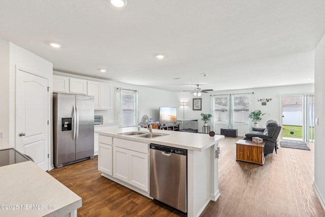 kitchen featuring dark wood finished floors, appliances with stainless steel finishes, open floor plan, and a sink