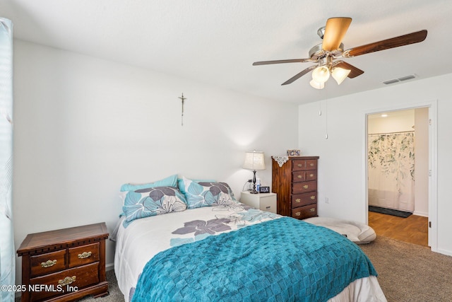 bedroom featuring carpet, ensuite bath, visible vents, and a ceiling fan