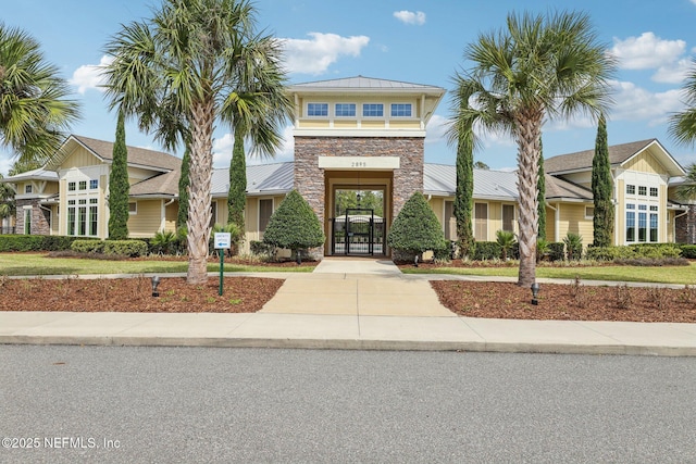 view of front of home featuring a standing seam roof, a gate, metal roof, a residential view, and stone siding