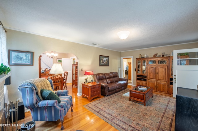 living room with arched walkways, visible vents, a textured ceiling, wood finished floors, and a chandelier