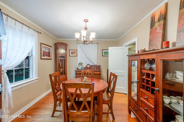 dining room featuring light wood-style floors, a chandelier, crown molding, and baseboards