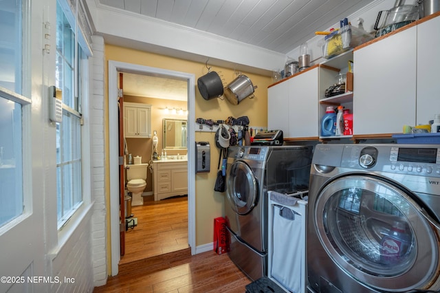 washroom featuring cabinet space, wood ceiling, wood finished floors, crown molding, and washing machine and dryer