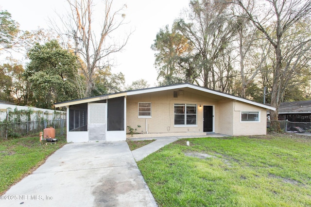 view of front of property with a sunroom, brick siding, fence, and a front lawn