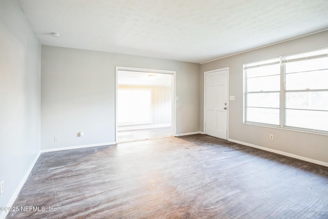 spare room featuring baseboards, a textured ceiling, and wood finished floors