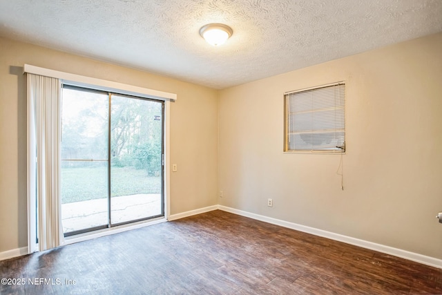 spare room featuring a textured ceiling, wood finished floors, and baseboards