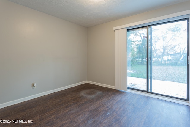 spare room featuring baseboards, dark wood finished floors, and a healthy amount of sunlight