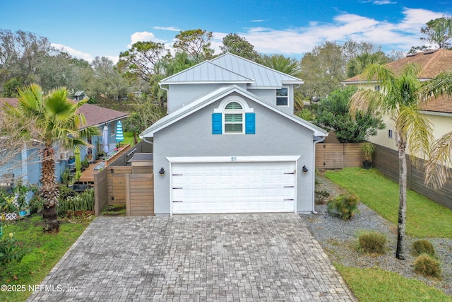 traditional-style house with a garage, fence, decorative driveway, and stucco siding