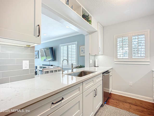 kitchen with tasteful backsplash, white cabinets, a sink, and stainless steel dishwasher