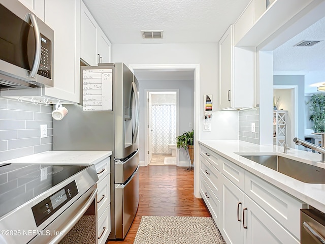 kitchen featuring appliances with stainless steel finishes, white cabinets, visible vents, and a sink