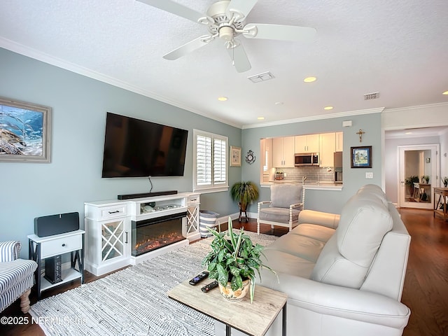 living area featuring visible vents, wood finished floors, and ornamental molding