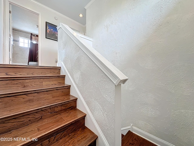 stairway with ornamental molding and wood finished floors