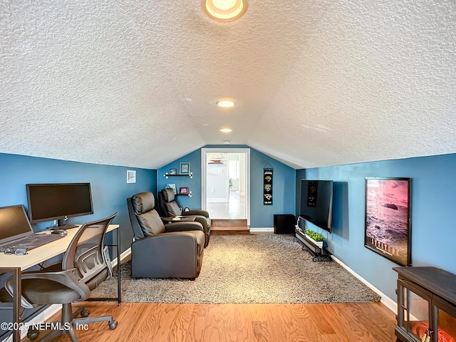 home office featuring lofted ceiling, a textured ceiling, baseboards, and wood finished floors