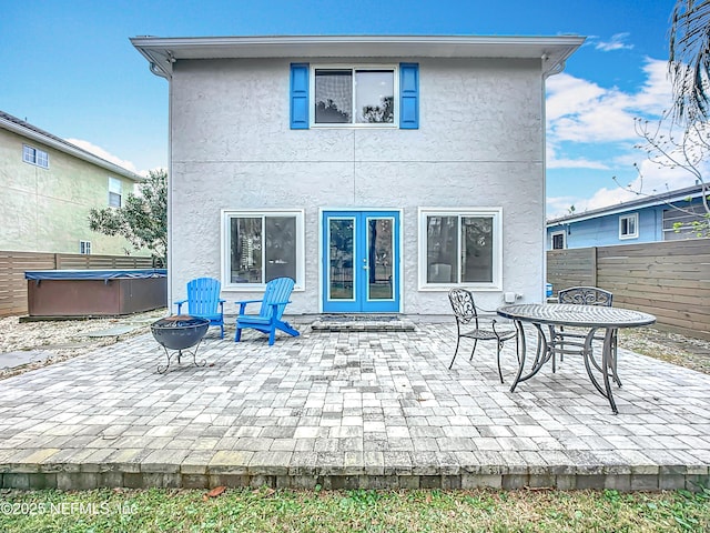 back of house featuring a patio, stucco siding, fence, and a hot tub