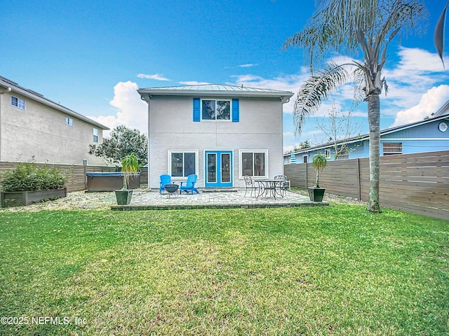 back of house featuring a hot tub, a lawn, a patio, a fenced backyard, and metal roof