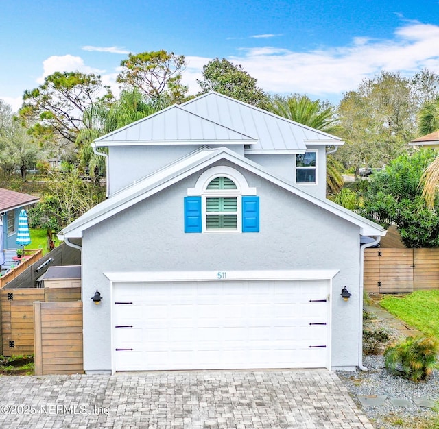 garage with decorative driveway and fence