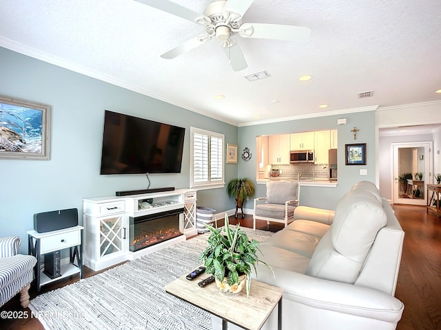 living area featuring visible vents, ornamental molding, and wood finished floors