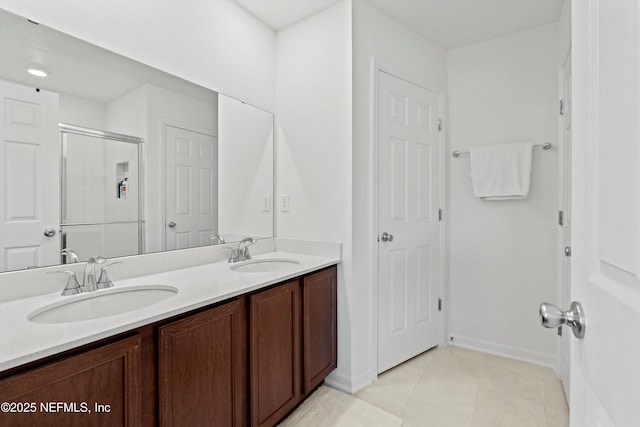 bathroom featuring double vanity, a shower stall, a sink, and tile patterned floors