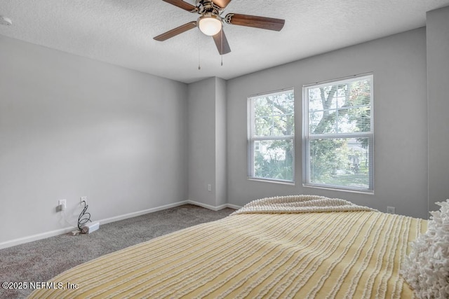 unfurnished bedroom featuring a textured ceiling, carpet flooring, a ceiling fan, and baseboards