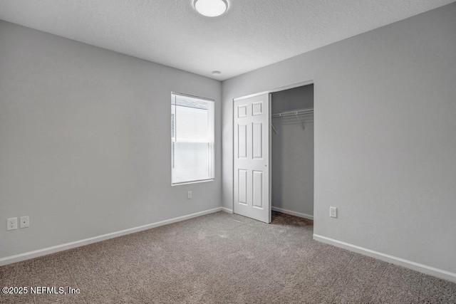 unfurnished bedroom with a textured ceiling, a closet, carpet, and baseboards