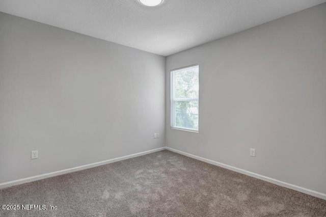 carpeted spare room featuring baseboards