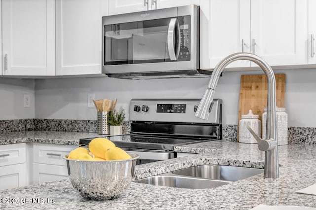 kitchen featuring stainless steel appliances, light stone countertops, and white cabinets