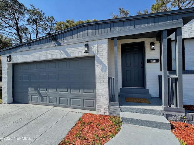 property entrance with concrete driveway, brick siding, and an attached garage