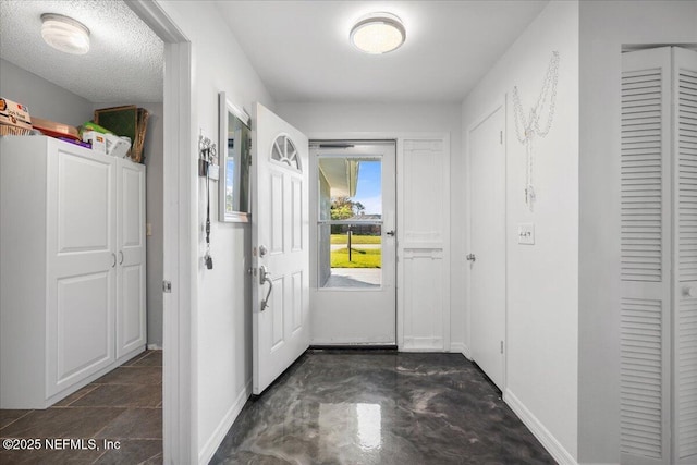 foyer featuring concrete flooring, a textured ceiling, and baseboards