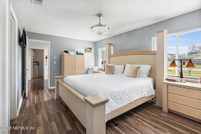 bedroom featuring dark wood-type flooring, multiple windows, a textured ceiling, and baseboards