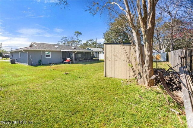 view of yard with central air condition unit, an outdoor structure, a storage unit, and fence