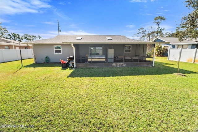 back of house featuring a sunroom, a fenced backyard, a lawn, and stucco siding