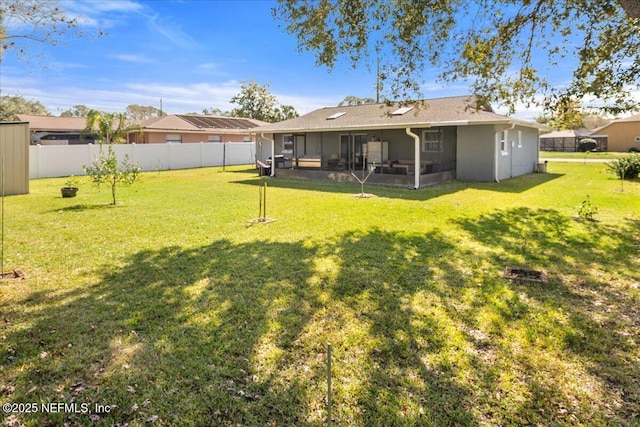 back of house featuring a sunroom, fence, and a lawn