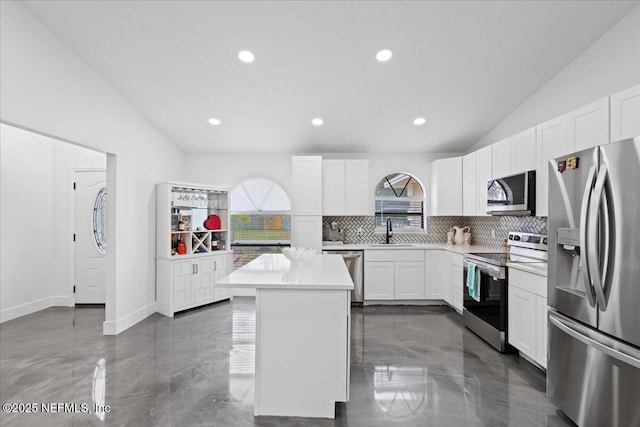 kitchen featuring a center island, light countertops, decorative backsplash, appliances with stainless steel finishes, and a sink