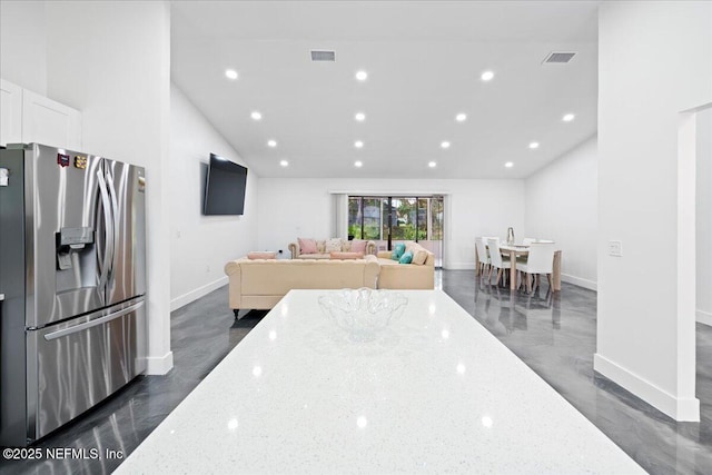 kitchen featuring light stone countertops, visible vents, stainless steel refrigerator with ice dispenser, and white cabinetry