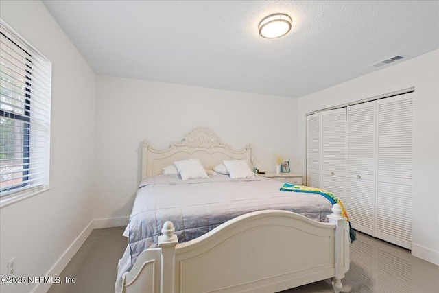 bedroom featuring a textured ceiling, a closet, visible vents, and baseboards