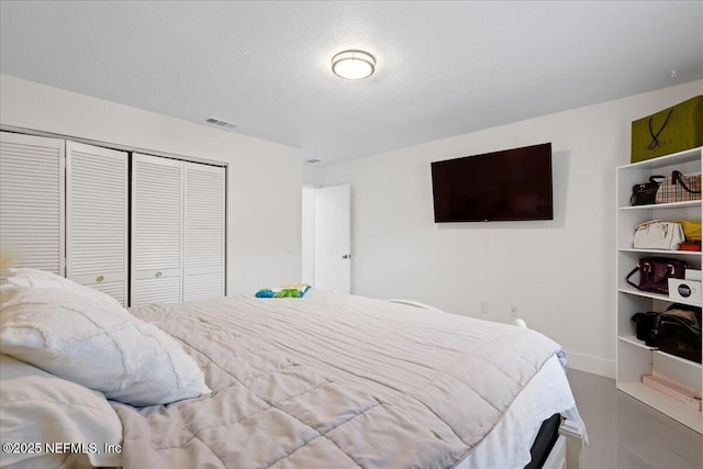 bedroom with baseboards, a textured ceiling, visible vents, and a closet