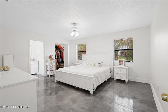 bedroom with a textured ceiling, connected bathroom, baseboards, a spacious closet, and a closet