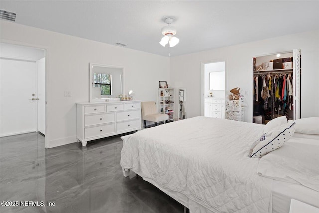 bedroom with concrete flooring, a spacious closet, visible vents, and baseboards