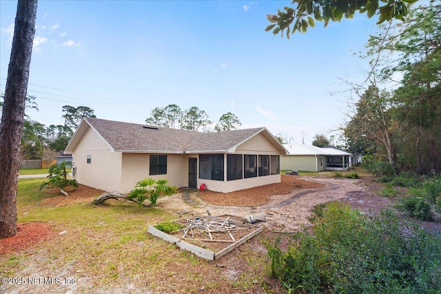 back of property with a sunroom and stucco siding