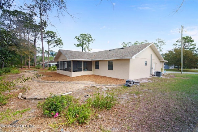 back of property featuring a sunroom, a yard, central AC unit, and stucco siding