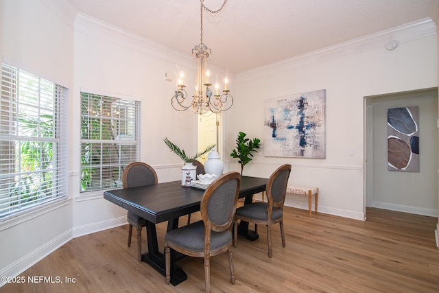 dining space with ornamental molding, light wood-type flooring, a notable chandelier, and baseboards