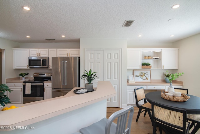 kitchen with appliances with stainless steel finishes, light wood-style floors, visible vents, and white cabinets