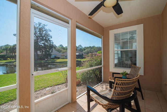 sunroom / solarium with ceiling fan and a water view