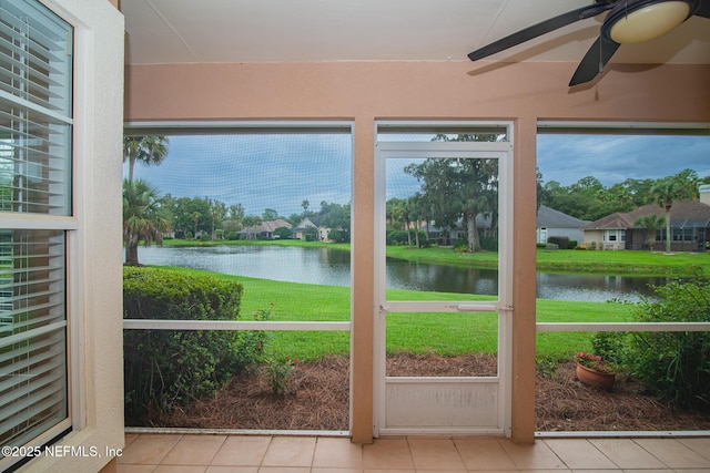 unfurnished sunroom with a ceiling fan and a water view