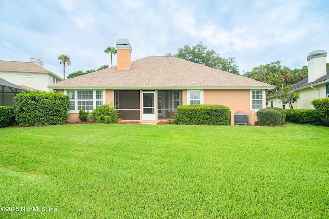 back of house featuring a chimney, stucco siding, a lawn, central AC unit, and a sunroom