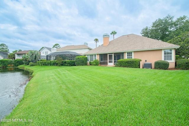 rear view of house featuring a yard, a chimney, stucco siding, a water view, and cooling unit