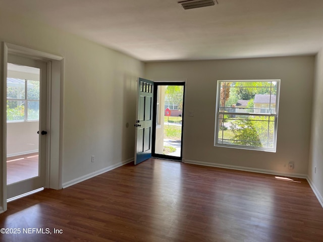 empty room with plenty of natural light and dark wood finished floors