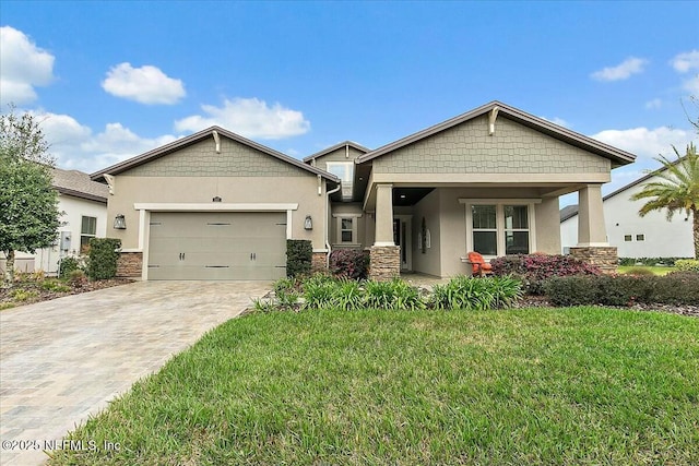 craftsman-style home with a front lawn, decorative driveway, an attached garage, and stucco siding